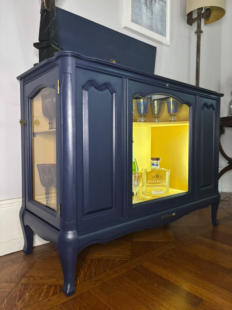 Vintage Victrola transformed into a striking liquor cabinet with Navy Blue and Carnaby Yellow finishes, glass shelves, and remote-controlled lighting