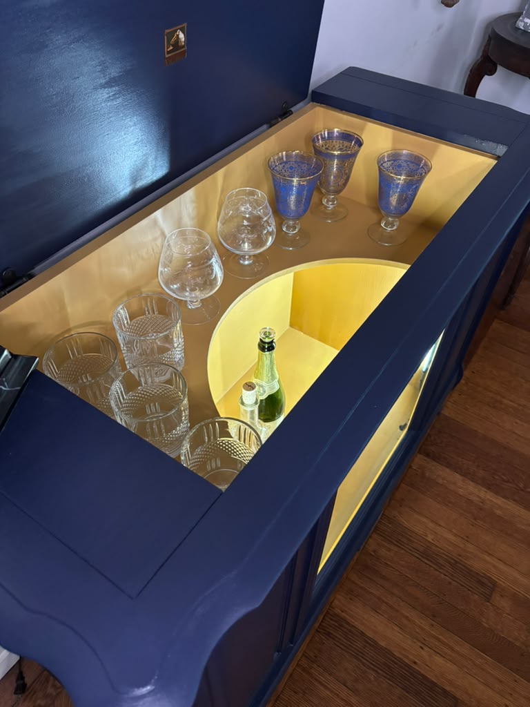 Vintage Victrola transformed into a striking liquor cabinet with Navy Blue and Carnaby Yellow finishes, glass shelves, and remote-controlled lighting