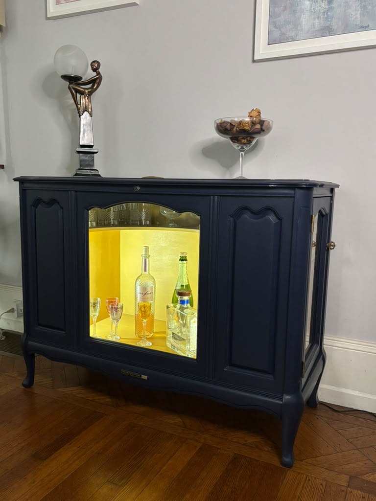 Vintage Victrola transformed into a striking liquor cabinet with Navy Blue and Carnaby Yellow finishes, glass shelves, and remote-controlled lighting